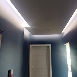 USŁUGI TRANSPORTOWE Sylwester Zieliński - Nowoczesne oświetlenie sufitowe LED w korytarzu z ciemnoniebieskimi ścianami i białą, minimalistyczną stolarką drzwiową.