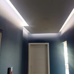 Nowoczesne oświetlenie sufitowe LED w korytarzu z ciemnoniebieskimi ścianami i białą, minimalistyczną stolarką drzwiową.