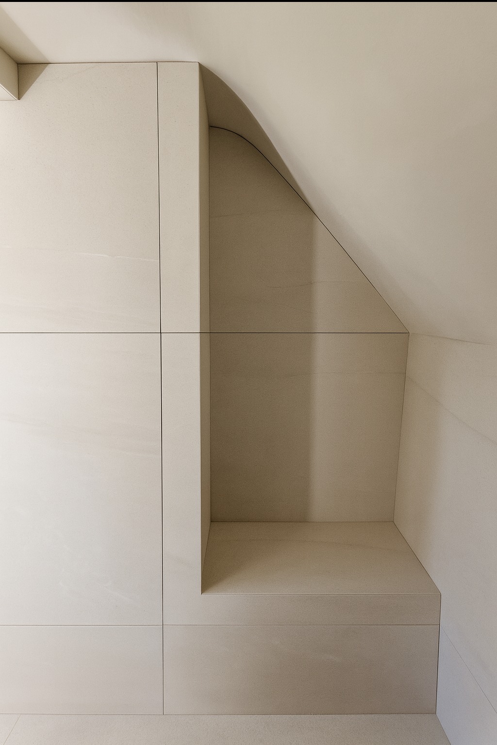 Narożna wnęka w łazience wykończona jasnymi, beżowymi płytkami. Minimalistyczny design, precyzyjne fugi, oświetlenie wewnątrz wnęki.