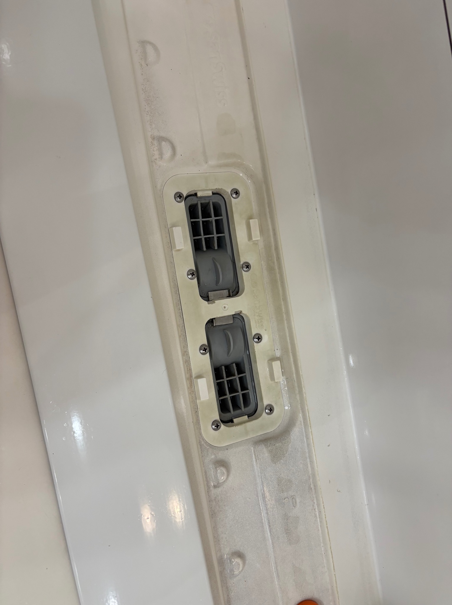 Biała powierzchnia z zamontowanymi kratkami wentylacyjnymi, widoczne ślady zabrudzeń i osadów przed czyszczeniem. Detal wnętrza wymagający odświeżenia.