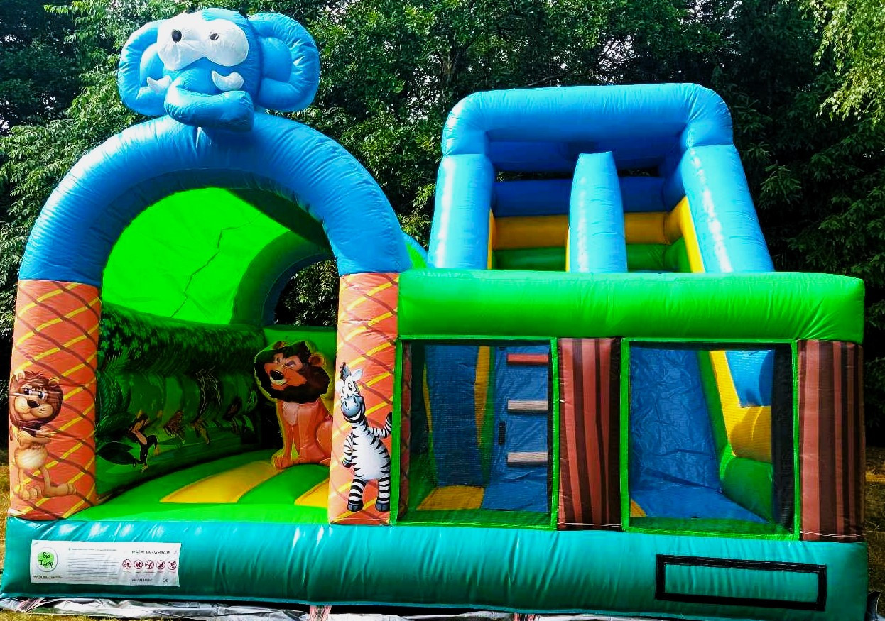 Kolorowy dmuchany plac zabaw Safari z motywem zwierząt: słoń na szczycie wejścia, lew i zebra na ściankach, zjeżdżalnia i strefa do skakania, zielone tło drzew.