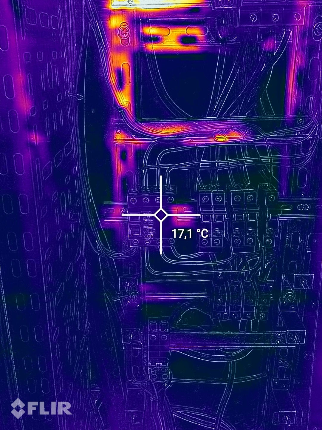 Termowizyjne zdjęcie rozdzielnicy elektrycznej, ukazujące temperaturę 17,1°C, z widocznymi przewodami i elementami zabezpieczeń.