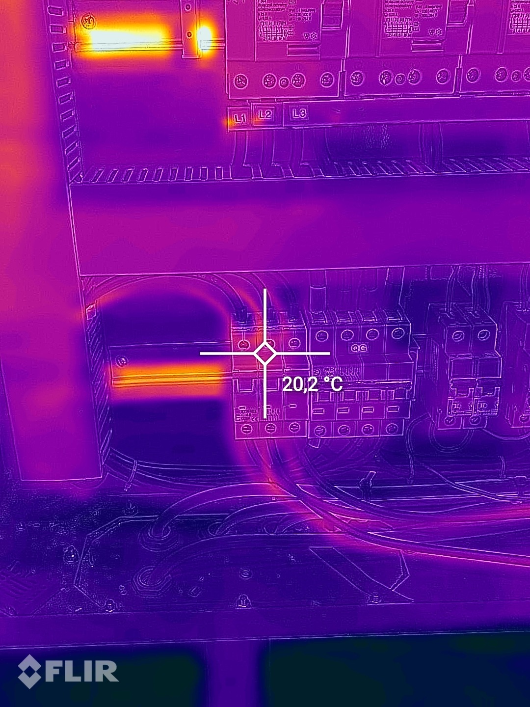 Termowizja rozdzielnicy elektrycznej, widoczne połączenia i przewody, z zaznaczonym punktem pomiaru temperatury 20,2°C, wykonana kamerą FLIR.