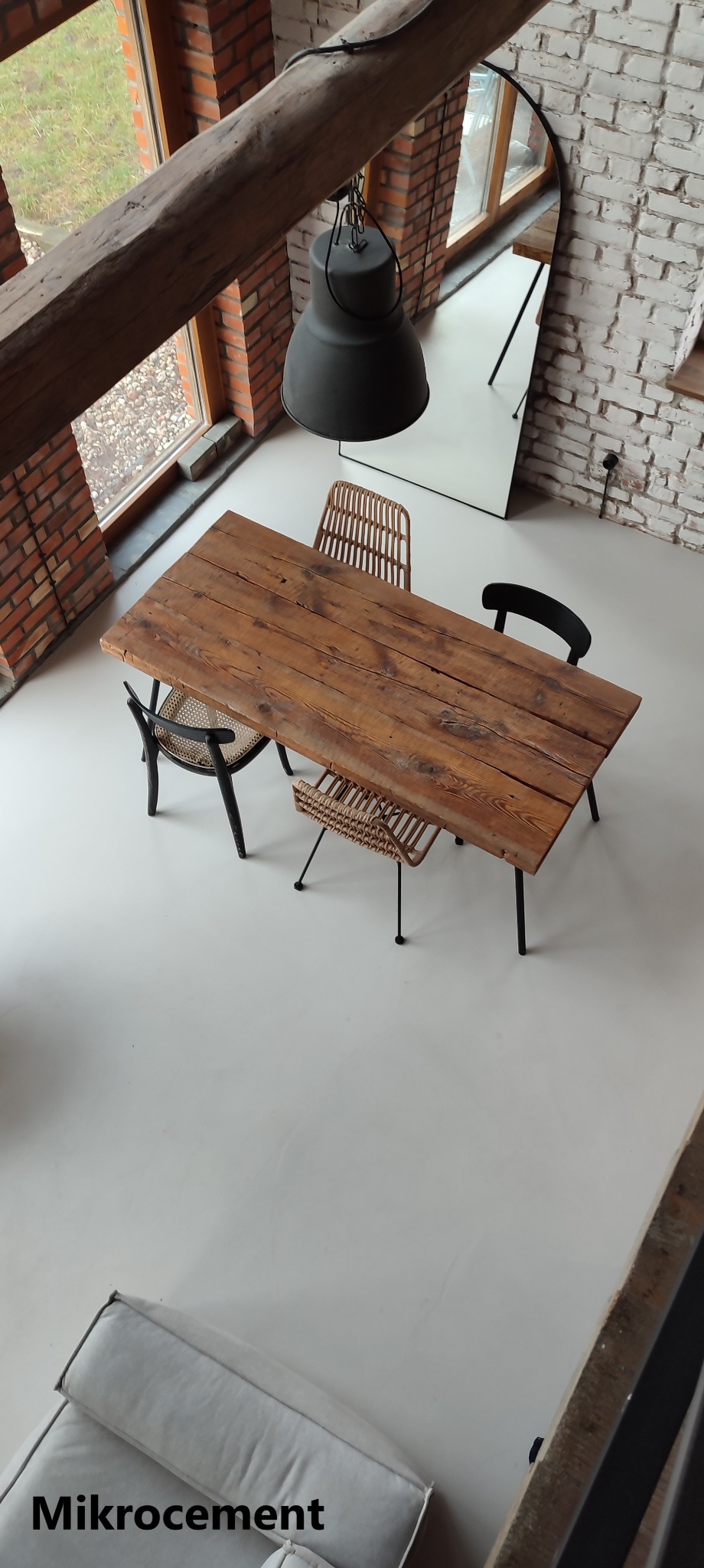 Jasnoszara podłoga w loftowym wnętrzu z drewnianym stołem i krzesłami, widok z góry na gładką powierzchnię.