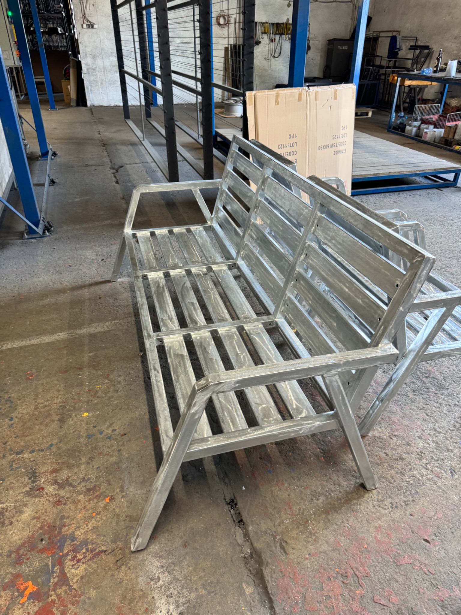 Surowa metalowa konstrukcja ławki ogrodowej w warsztacie w Czerwionce-Leszczynach, widoczne ślady obróbki na metalu, w tle elementy konstrukcyjne i narzędzia.