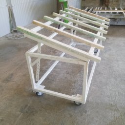 Stal fox - Stalowa konstrukcja na kółkach z drewnianymi poprzeczkami, prawdopodobnie w warsztacie, w trakcie budowy lub malowania.