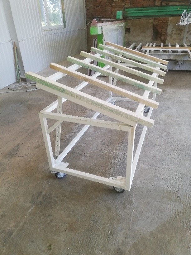 Stalowa konstrukcja na kółkach z drewnianymi poprzeczkami, prawdopodobnie w warsztacie, w trakcie budowy lub malowania.