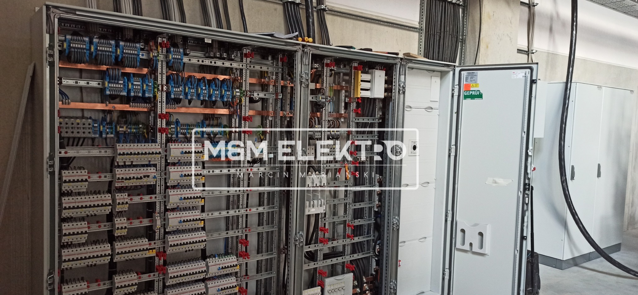 Otwarta szafa sterownicza z widocznymi zabezpieczeniami, przewodami, listwami zaciskowymi i elementami montażowymi na metalowej konstrukcji szkieletowej.