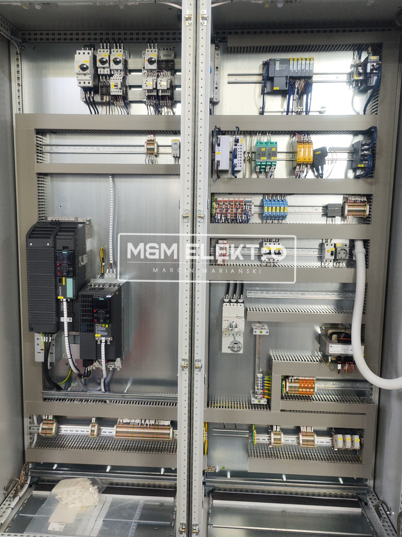 Wnętrze szafy sterowniczej z zainstalowanymi modułami, zabezpieczeniami i okablowaniem, widoczne sterowniki Siemens i elementy Eaton, przewody ułożone w korytkach, w dolnej części woreczek z opisami.