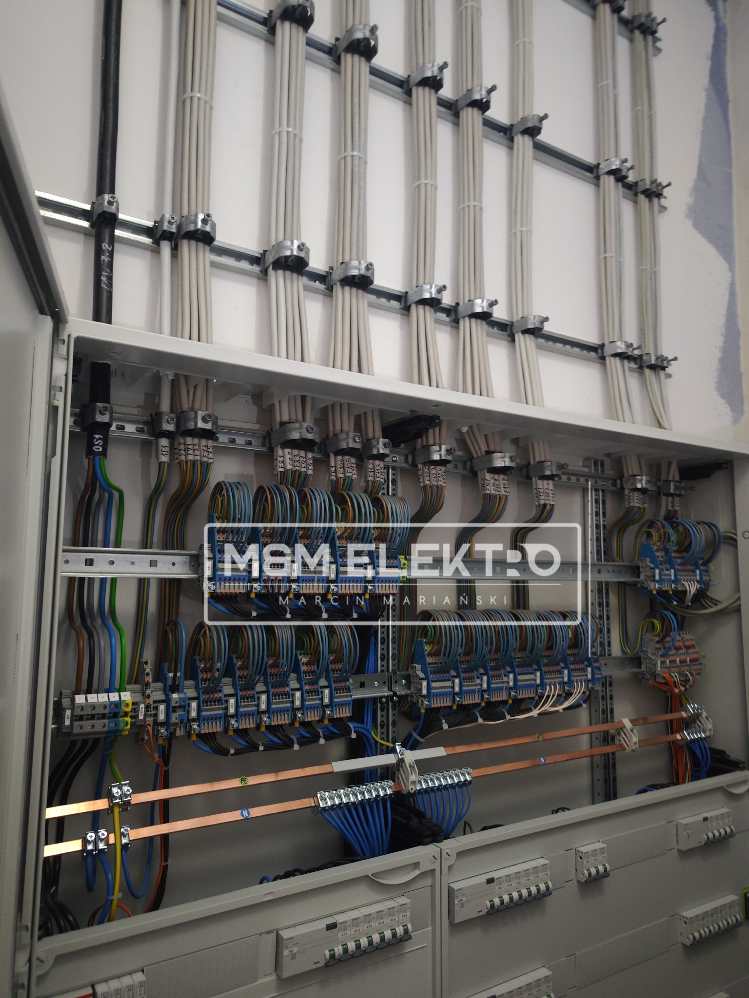 Rozdzielnia elektryczna z przewodami ułożonymi pionowo i przymocowanymi do szyn, widok na wnętrze szafy z bezpiecznikami i okablowaniem, instalacja wykonana w Działdowie.