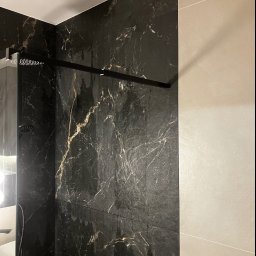 Bogdan Andriushkin - Nowoczesna kabina prysznicowa z czarnymi płytkami imitującymi marmur i beżowymi płytkami. Widoczna deszczownica i szklana ściana kabiny.