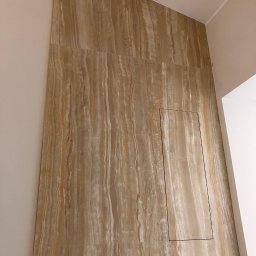 Bogdan Andriushkin - Ściana wykończona płytami imitującymi trawertyn, z ukrytymi drzwiczkami rewizyjnymi. Ukośne ułożenie płyt tworzy unikalny efekt wizualny.