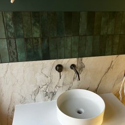 Bogdan Andriushkin - Nowoczesna łazienka: umywalka nablatowa, bateria w kolorze antracytu, ściana z płytek imitujących marmur i zielona glazura wertykalna. Widoczne przewody elektryczne.