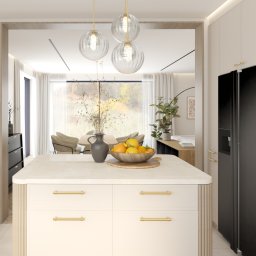 Kinga Jaźwiec - Jasna kuchnia z wyspą, złotymi uchwytami i czarnym sprzętem AGD Miele, widok na jadalnię z oknem na ogród.