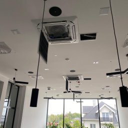 VENTIMAR SPÓŁKA Z OGRANICZONĄ ODPOWIEDZIALNOŚCIĄ - Kasetonowa jednostka klimatyzacyjna w suficie podwieszanym restauracji, z otwartym panelem dostępowym, widoczne wnętrze urządzenia i elementy instalacji.