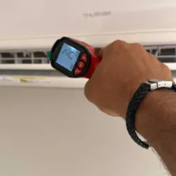 Pomiar temperatury klimatyzatora ściennego termometrem laserowym. Na ekranie termometru widoczna temperatura 24,2 stopnie Celsjusza.