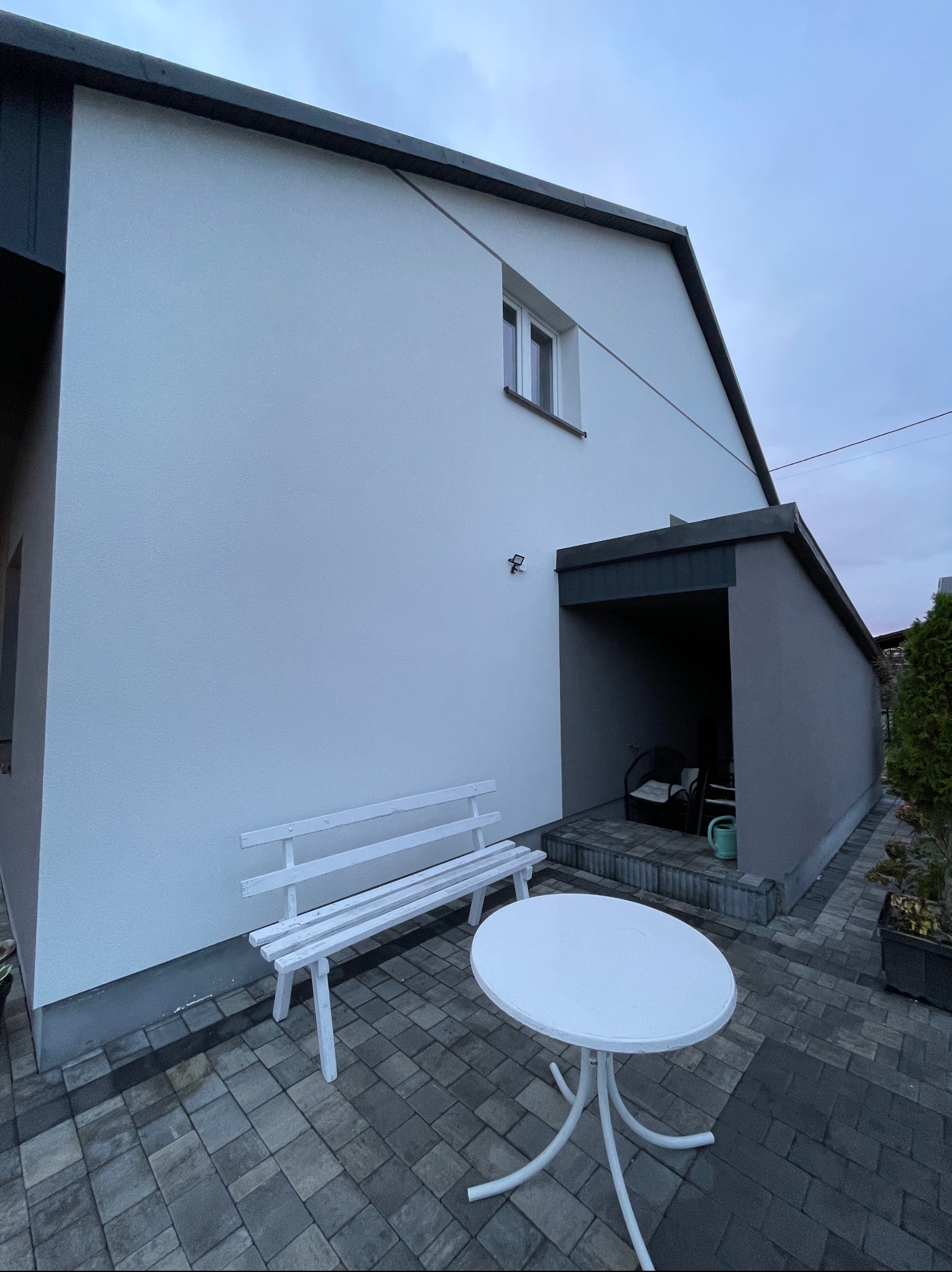 Dom jednorodzinny w Trzebosi po ociepleniu elewacji, z widoczną białą ławką i stolikiem na kostce brukowej.