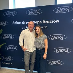 Babka od Wykończeń Magdalena Mazur - Salon drzwi Wepa Rzeszów prezentuje zespół na tle ściany z logo. Profesjonalny montaż drzwi w Rzeszowie. Adres salonu widoczny na ścianie.