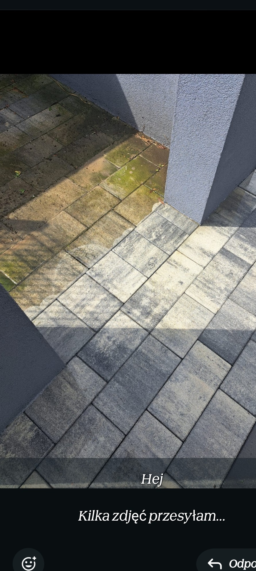 Część kostki brukowej przed i po czyszczeniu, widoczna różnica w kolorze i usunięty mech, szara ściana z prawej strony.