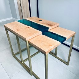 OSTRY SPAW - Zestaw dwóch stolików kawowych z drewnianymi blatami i złotymi metalowymi nogami, wypełnionych turkusową żywicą epoksydową, ustawionych jeden pod drugim.