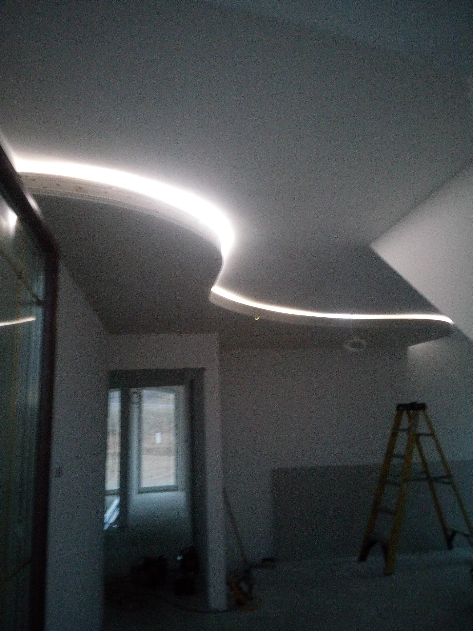 Sufit podwieszany z dekoracyjnym oświetleniem LED, widoczna drabina malarska i wstęp do kolejnego pomieszczenia.