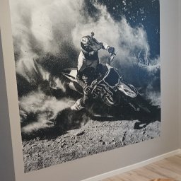 Marcin Polek Usługi Remontowo-Serwisowe MM - Czarno-biała fototapeta na ścianie przedstawiająca motocyklistę w kasku podczas jazdy w terenie, widoczny fragment krzesła i stołka na tle paneli podłogowych