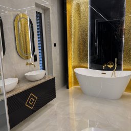Profesjonalna Firma Sprzątająca - Martyna Zasada - Luksusowa łazienka z wolnostojącą wanną, złotymi akcentami i marmurowymi płytkami. Umywalki nablatowe i czarna szafka z geometrycznym wzorem.