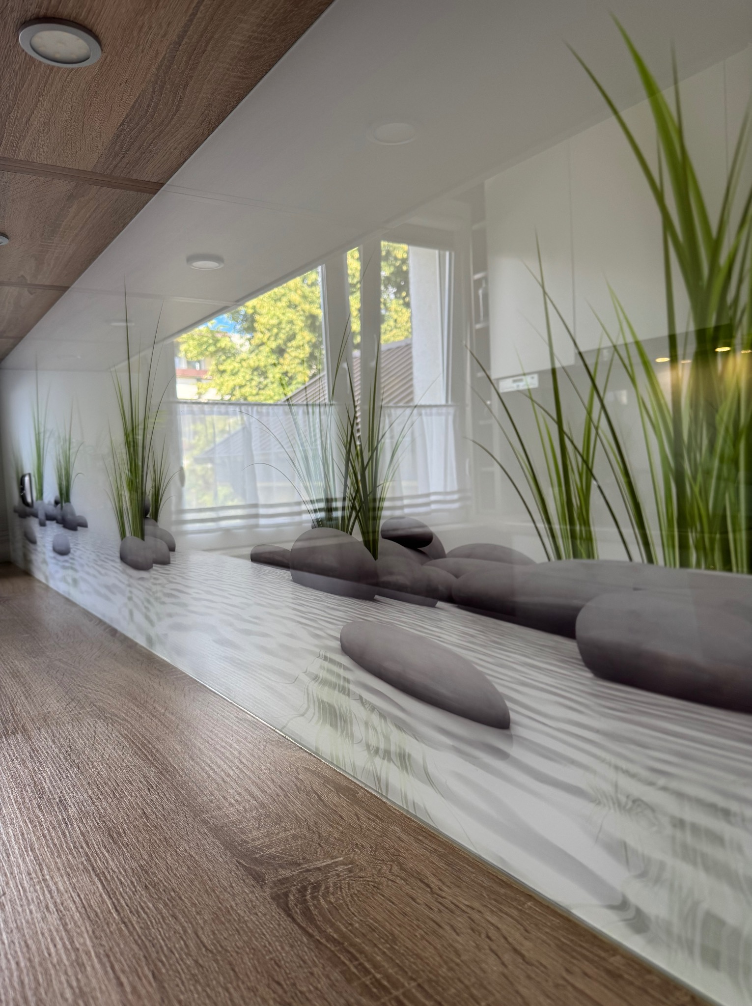 Szklany panel dekoracyjny z motywem zen w kuchni po sprzątaniu w Wieniawie. Rośliny i kamienie na tle okna. Nowoczesny design, czysta przestrzeń.