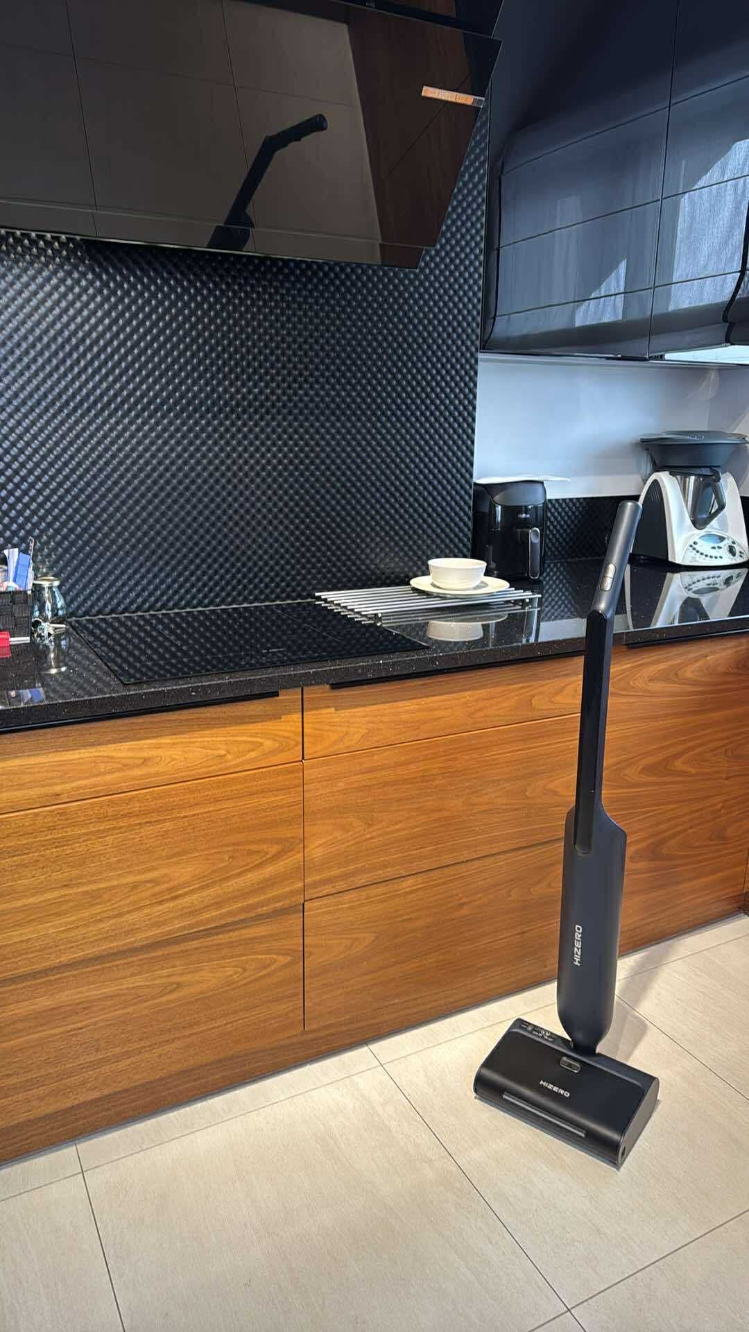 Bezprzewodowy mop HIZERO w nowoczesnej kuchni z drewnianymi szafkami i czarnym panelem. Sprzątanie mieszkania w Przysusze.