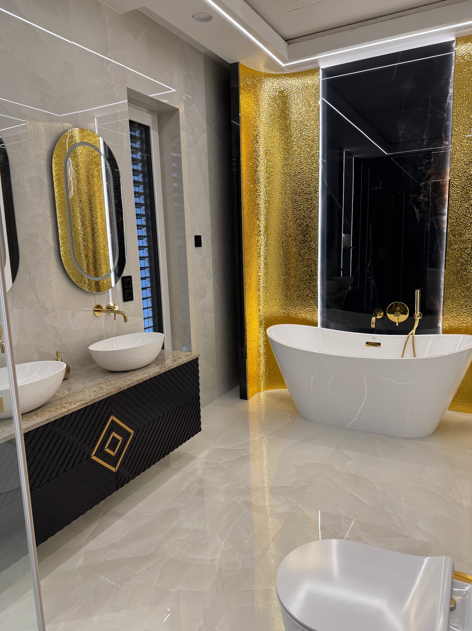 Luksusowa łazienka z wolnostojącą wanną, złotymi akcentami i marmurowymi płytkami. Umywalki nablatowe i czarna szafka z geometrycznym wzorem.