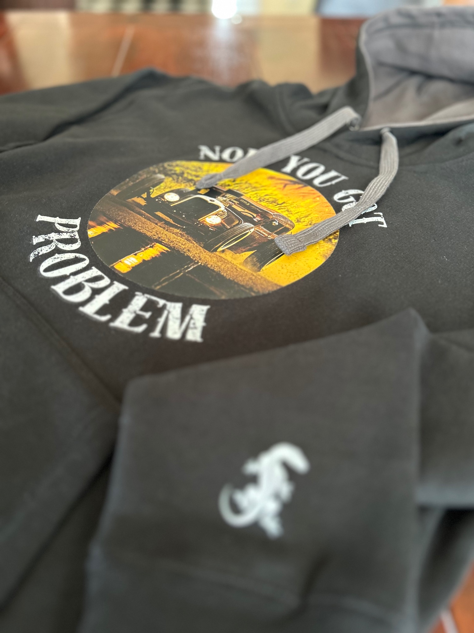 Czarna bluza z kapturem z nadrukiem auta i napisem 'Now you got problem'. Na rękawie małe białe logo.