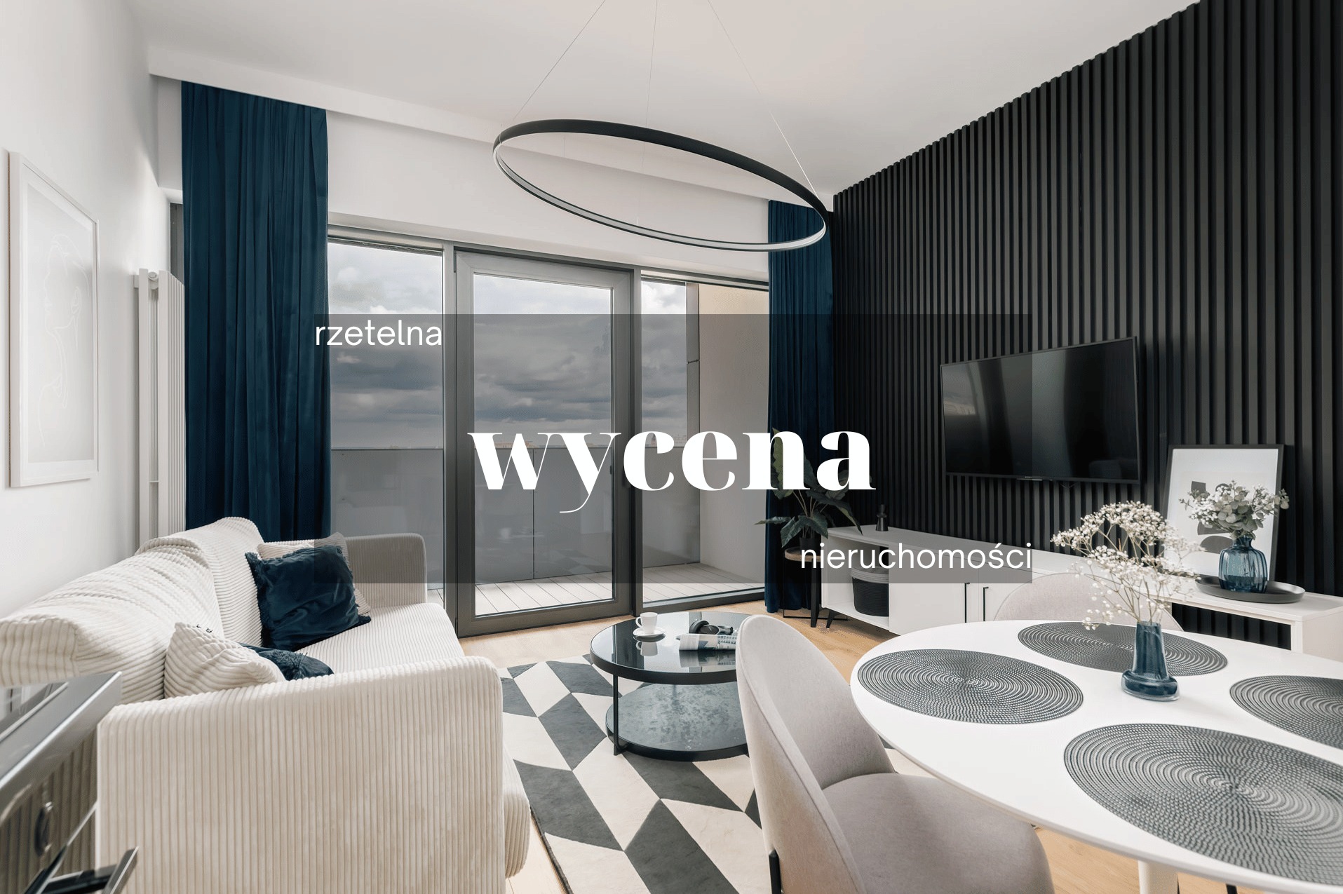 Nowoczesny salon z balkonem, szarą sofą z poduszkami, okrągłym stolikiem kawowym, dywanem w geometryczne wzory i czarną ścianą z telewizorem. Okrągła lampa sufitowa i widok na miasto z balkonu.