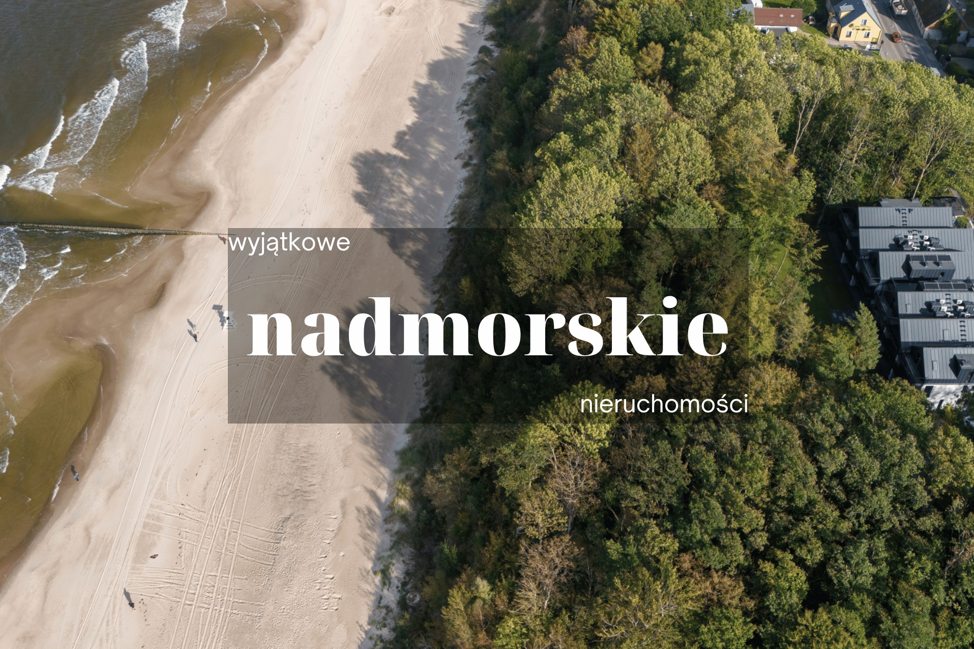 Widok z lotu ptaka na piaszczystą plażę z drewnianym falochronem, przylegający las i budynek mieszkalny z ciemną elewacją w tle.