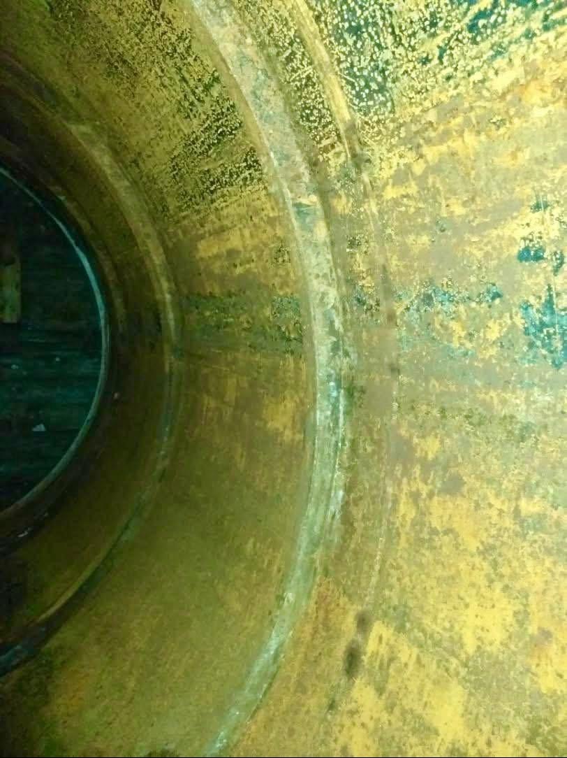 Wnętrze metalowej rury po piaskowaniu, widoczne ślady rdzy i pozostałości po procesie czyszczenia. Żółto-zielona powierzchnia z wyraźną teksturą.