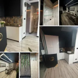 Nowoczesny salon kosmetyczny z białymi szafkami, czarnymi akcentami, drewnopodobną podłogą i szklanymi elementami, oświetlony ledowym światłem, wyposażony w stanowiska do manicure z białymi krzesłami.