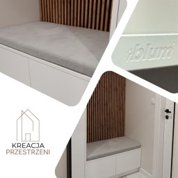 Twoje wyjątkowe meble - Biała szafa wnękowa z tapicerowanym siedziskiem i lamelami z naturalnego drewna, widoczne logo Blum, ujęcie z perspektywy wejścia do pomieszczenia.