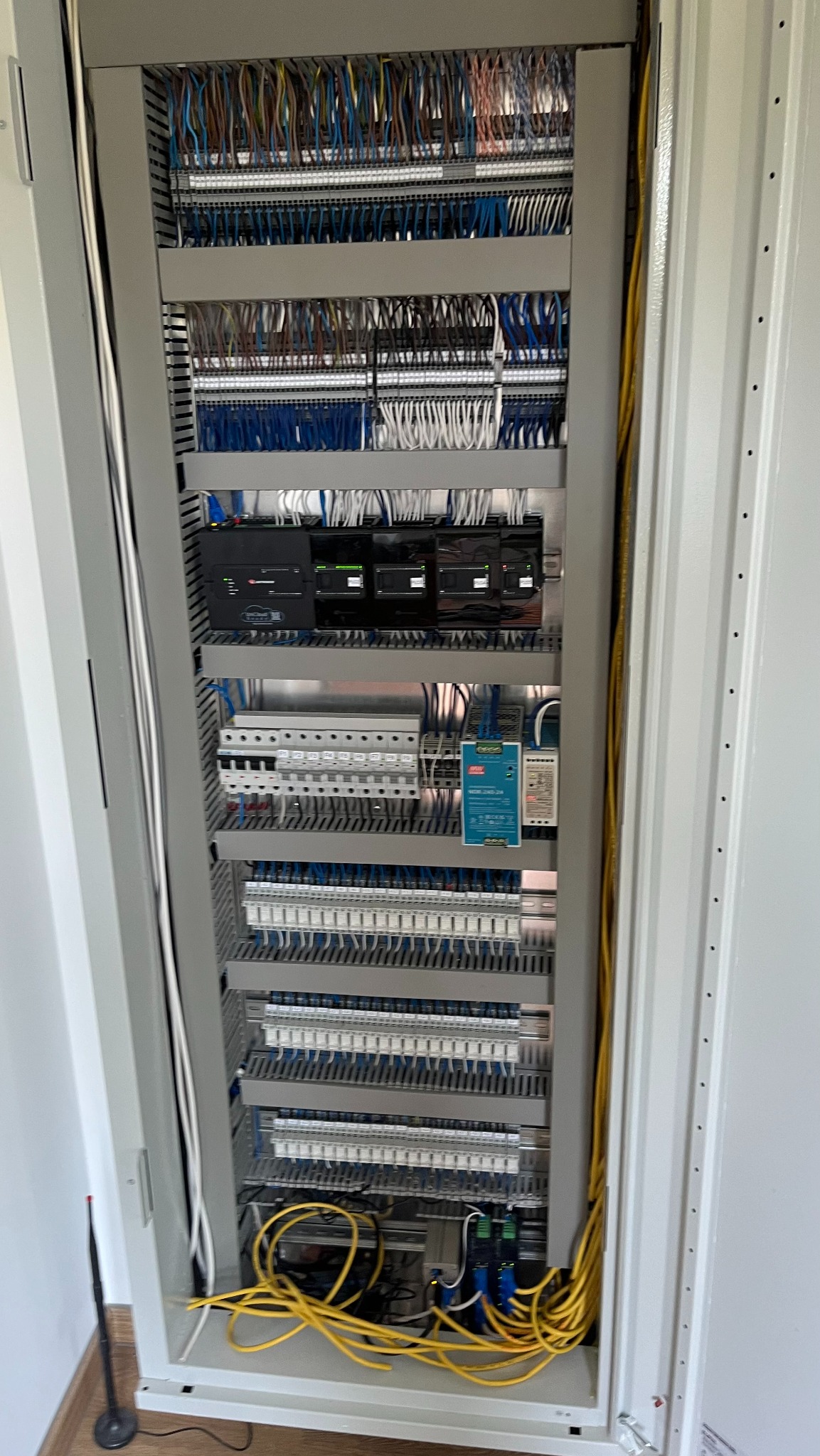 Otwarta szafa sterownicza z rozbudowanym okablowaniem, modułami sterującymi i listwami zaciskowymi, widoczne przewody w różnych kolorach oraz elementy montażowe.