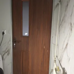 Drewniane drzwi wewnętrzne z szybką, zamontowane w łazience z marmurowymi płytkami, obok biały grzejnik i widoczny fragment pralki.