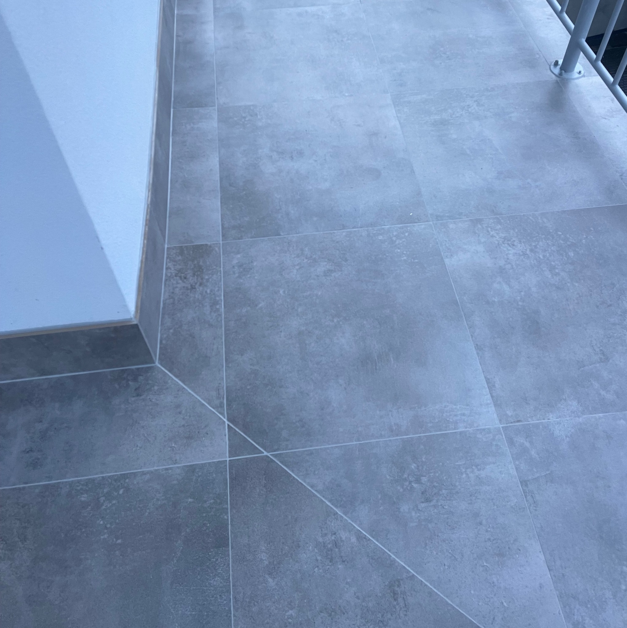 Szare, matowe płytki podłogowe ułożone na balkonie w Skarszewach, z widocznym fragmentem ściany i balustrady.