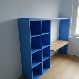 HiWall - Meble na Wymiar Wrocław - Niebieska zabudowa meblowa z regałem i biurkiem z drewnianym blatem, przymocowana do ściany w pokoju, widoczna z boku.