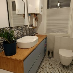 HiWall - Meble na Wymiar Wrocław - Nowoczesna łazienka z drewnianym blatem, umywalką nablatową, wzorzystymi płytkami i wiszącym piecem gazowym nad umywalką.