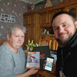 NORD ENERGY POLAND S. A. - Kobieta i mężczyzna prezentują materiały reklamowe firmy Nord Energy S.A. dotyczące oszczędności energii w domu, w tle widoczny jest klasyczny wystrój wnętrza.