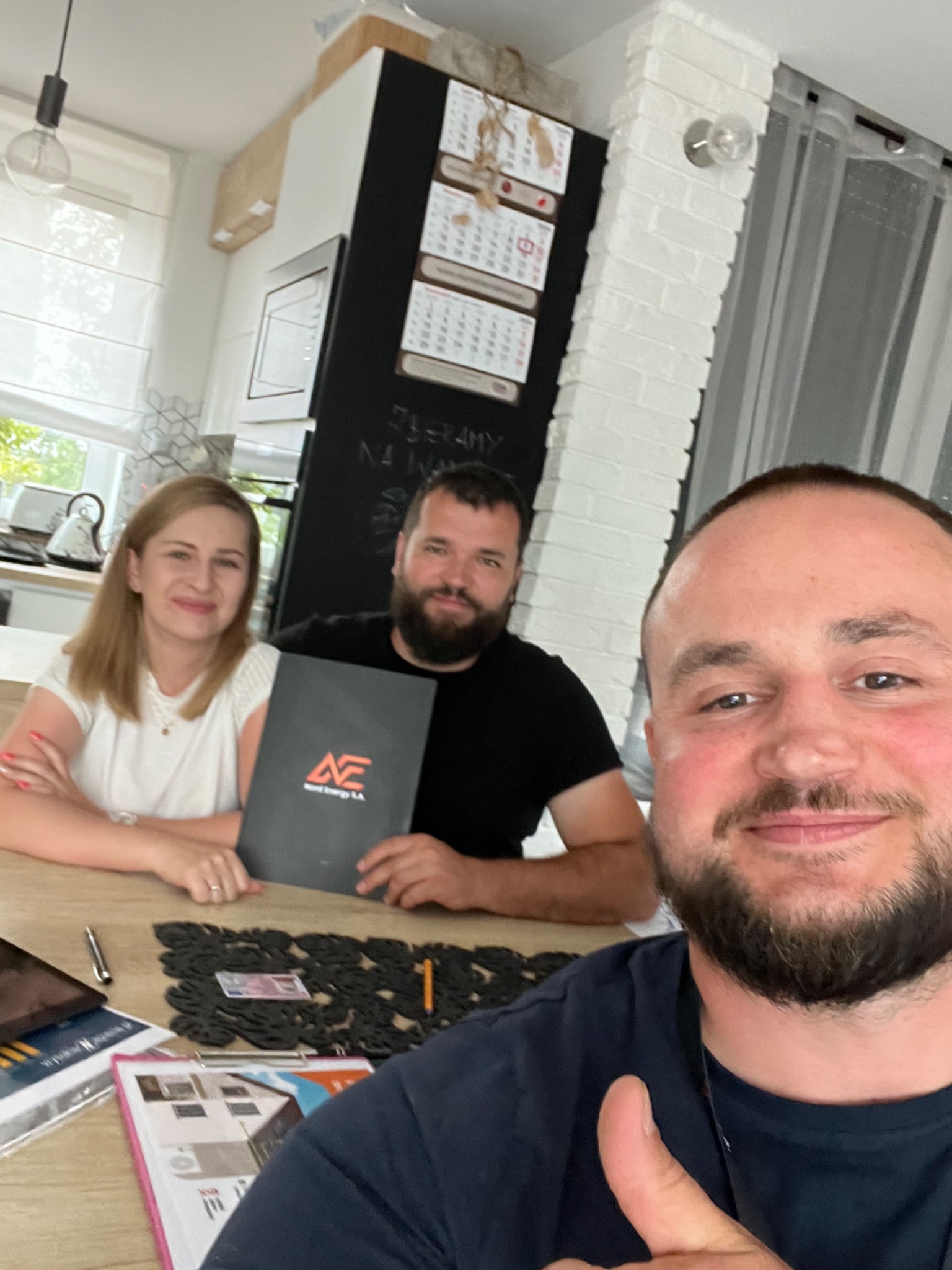 Ekipa z firmy z Gdańska prezentuje folder z logo podczas spotkania, widoczny uśmiech i gest aprobaty.