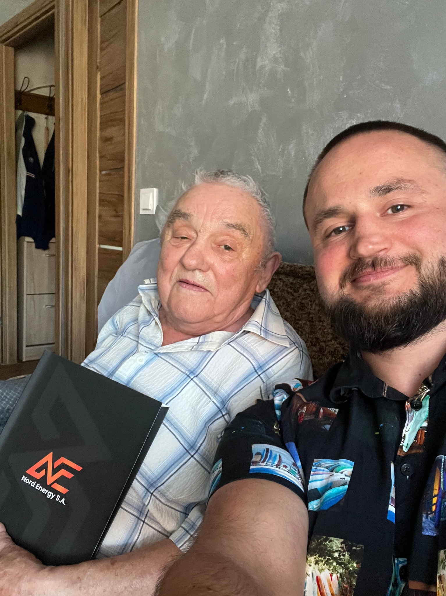 Mężczyzna robi selfie z starszym panem trzymającym czarny folder z logo Nord Energy S.A.