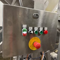 B_P ELEKTROINSTALACJE BARTOSZ PUCZKA - Panel sterowania ze stali nierdzewnej z przyciskami (włącz/wyłącz, ręka/auto, góra, dół, awaria) oraz wyłącznikiem bezpieczeństwa z żółtą obwódką, zamontowany na maszynie przemysłowej.