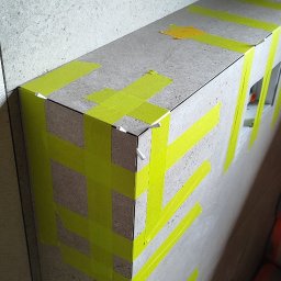 SK-Bud Sebastian Nienajadło - Wykończona obudowa z płytek, zabezpieczona taśmą i klipsami poziomującymi w trakcie prac glazurniczych w Jarosławiu. Widoczne fragmenty instalacji.