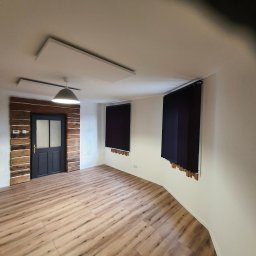 N-techniczne - Jasne panele podłogowe w nowo wykończonym pokoju z ciemnymi roletami i oknem w drewnianej obudowie. Minimalistyczny wystrój wnętrza.