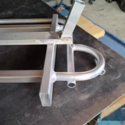 Aluminiowa konstrukcja spawana z profili zamkniętych i rur, widoczne spawy, na stole warsztatowym.