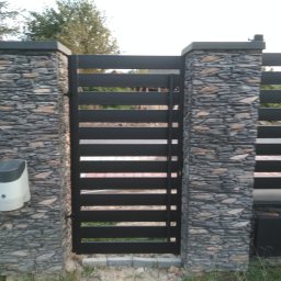 HYDROMIRO-SPAW Mirosław Rękawik - Nowoczesna brama wjazdowa z poziomych, czarnych profili, zamontowana pomiędzy kamiennymi słupkami z automatyką do otwierania, widoczna z zewnątrz posesji.