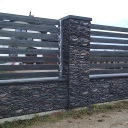 HYDROMIRO-SPAW Mirosław Rękawik - Nowoczesne ogrodzenie z poziomych, szarych desek i kamiennych słupków, widok z zewnątrz posesji na tle domu.